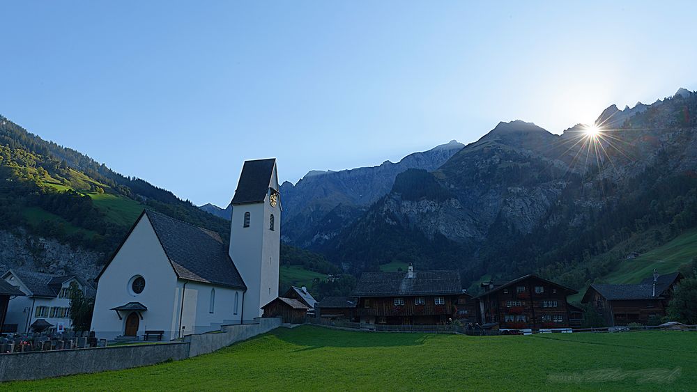 Sonne scheint durchs Martinsloch auf die Kirche von Elm