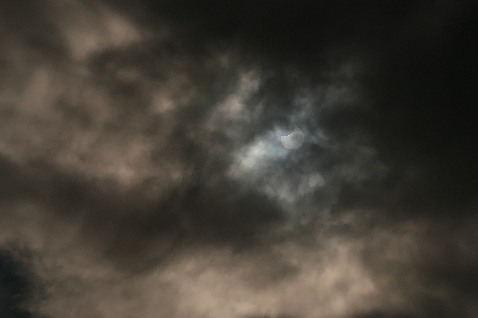 Sonne und Mond in dunklen Wolken