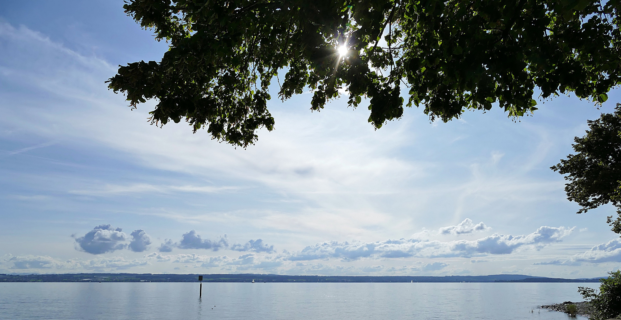 Sonne und Wolken über dem See.