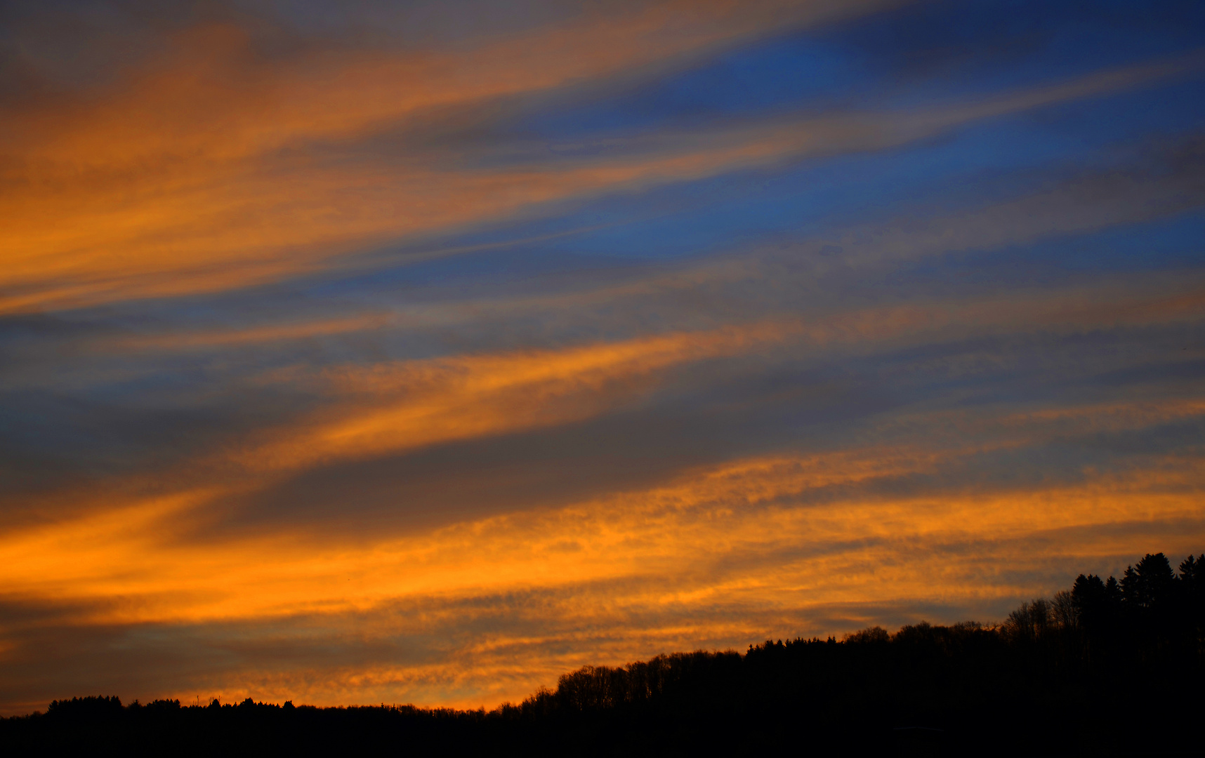 Sonnenaufgang über bewaldetenm Berg