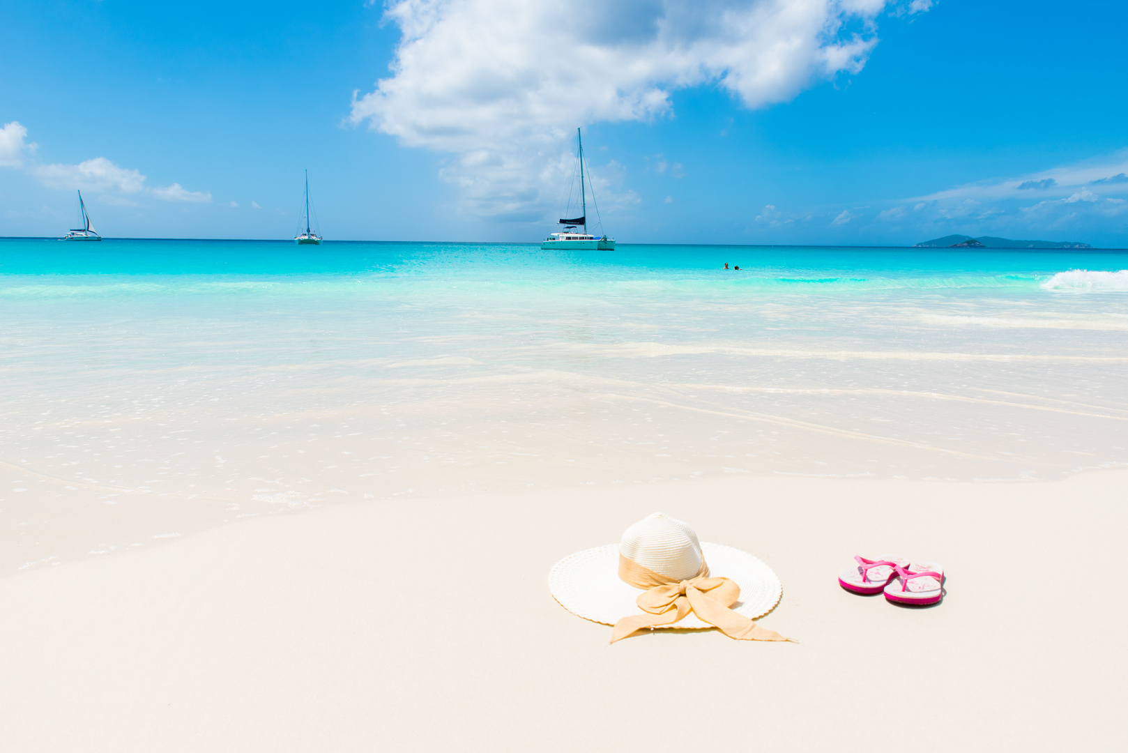 Sonnenhut und Flipflops am Strand