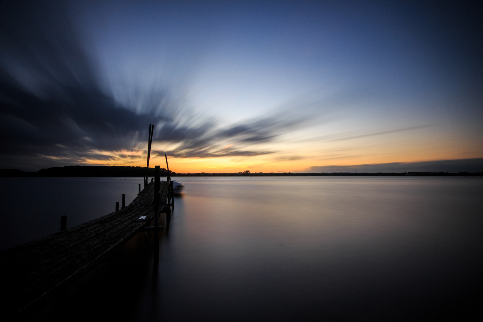 Sonnenuntergang am Steg mit einsamen Boot