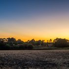 Sonnenuntergang hinter abgeernteten Feldern