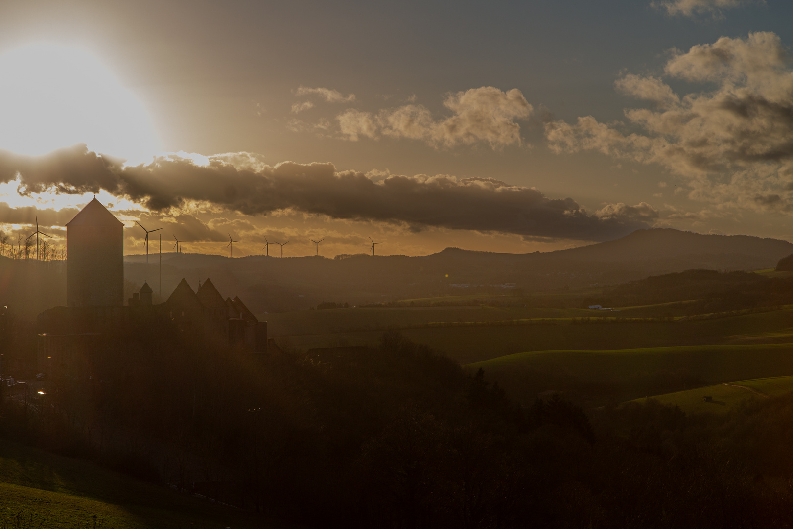 Sonnenuntergang mit Burg und Windrädern