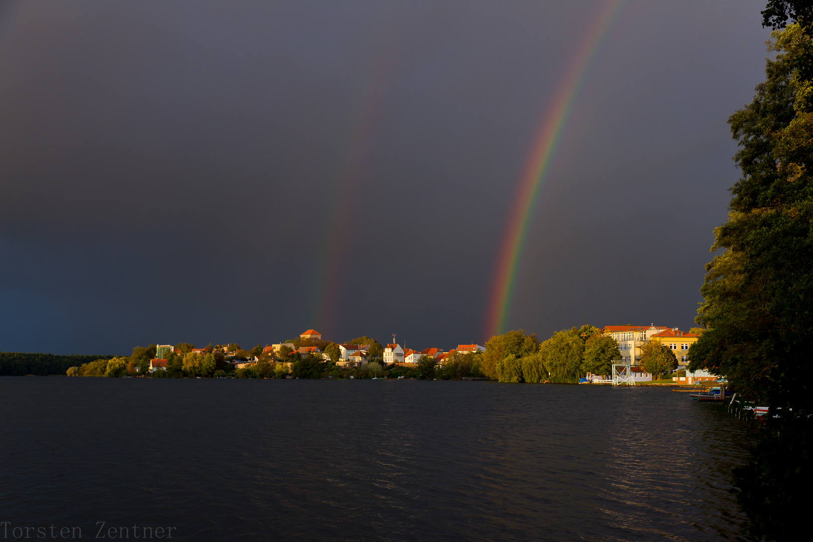 Sonnenuntergang mit Regenbogen am Straussee mit Stadtblick