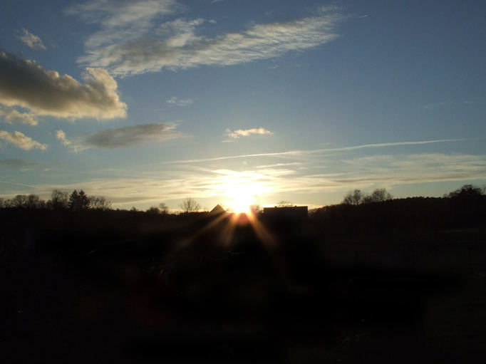 Sonnenuntergang über den Häusern vorm Wald