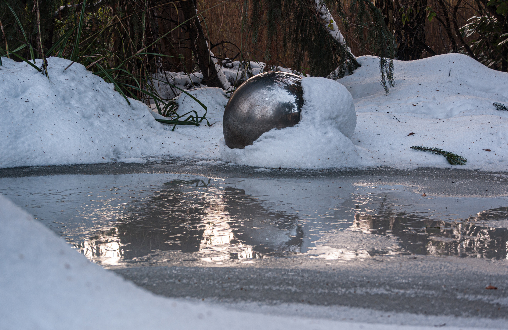 Spiegelkugel im verschneiten Gartenteich