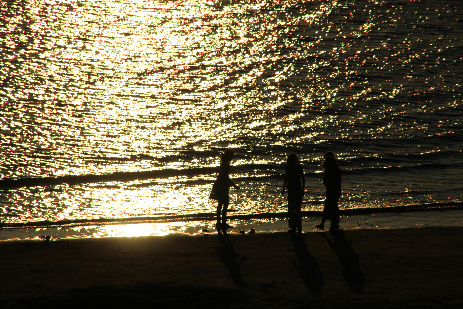 Spielende Kinder am Strand in der Abenddämmerung.