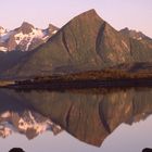 Spitze Berge spiegeln sich bei Sonnenschein auf den Lofoten