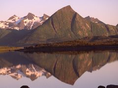 Spitze Berge spiegeln sich bei Sonnenschein auf den Lofoten