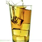 Spritzer mit einem Eiswürfel. Bourbon whiskey splashes with an ice cube.