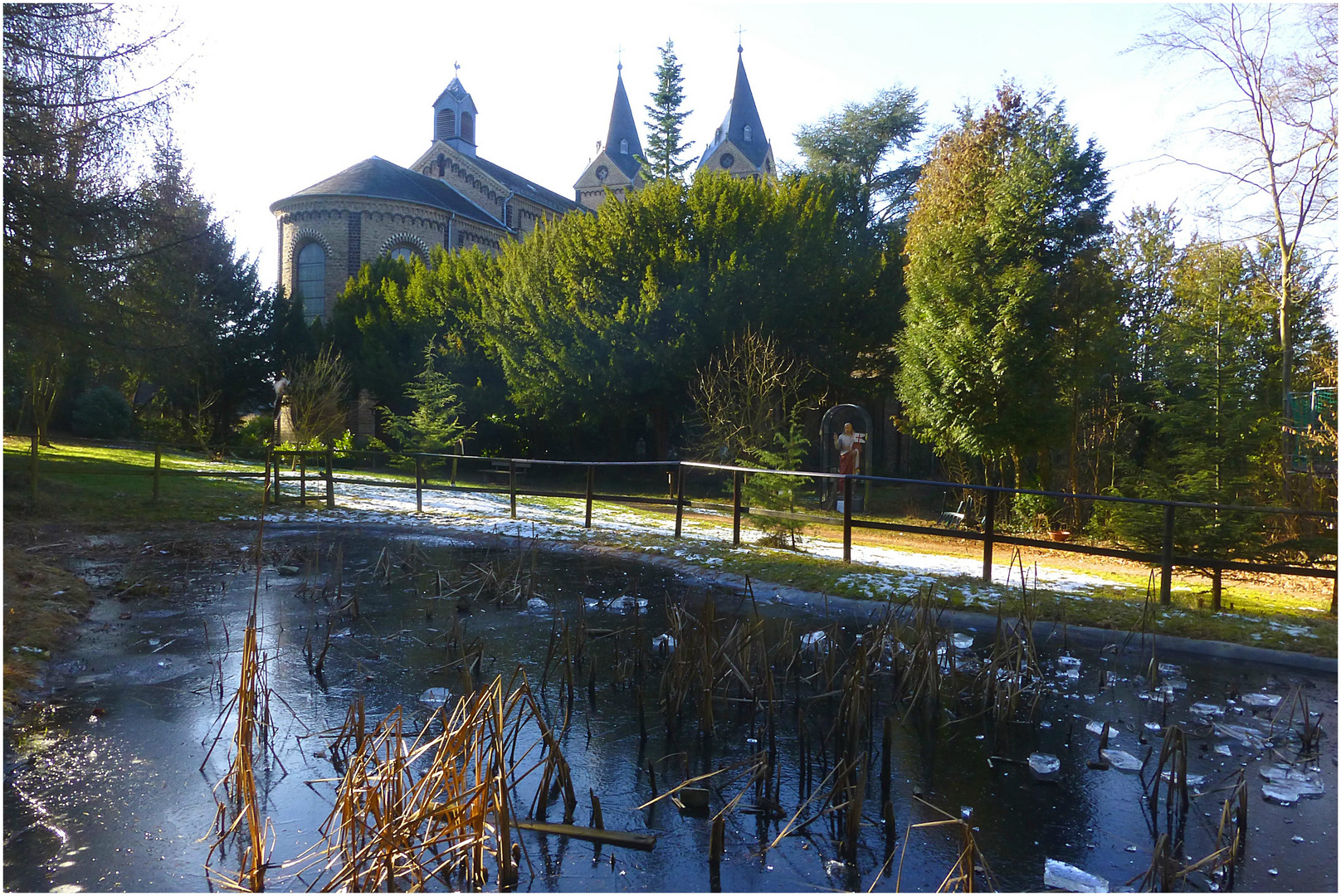 St. Nikolauskirche Arenberg über dem zugefrorenen Teich im Ostergarten