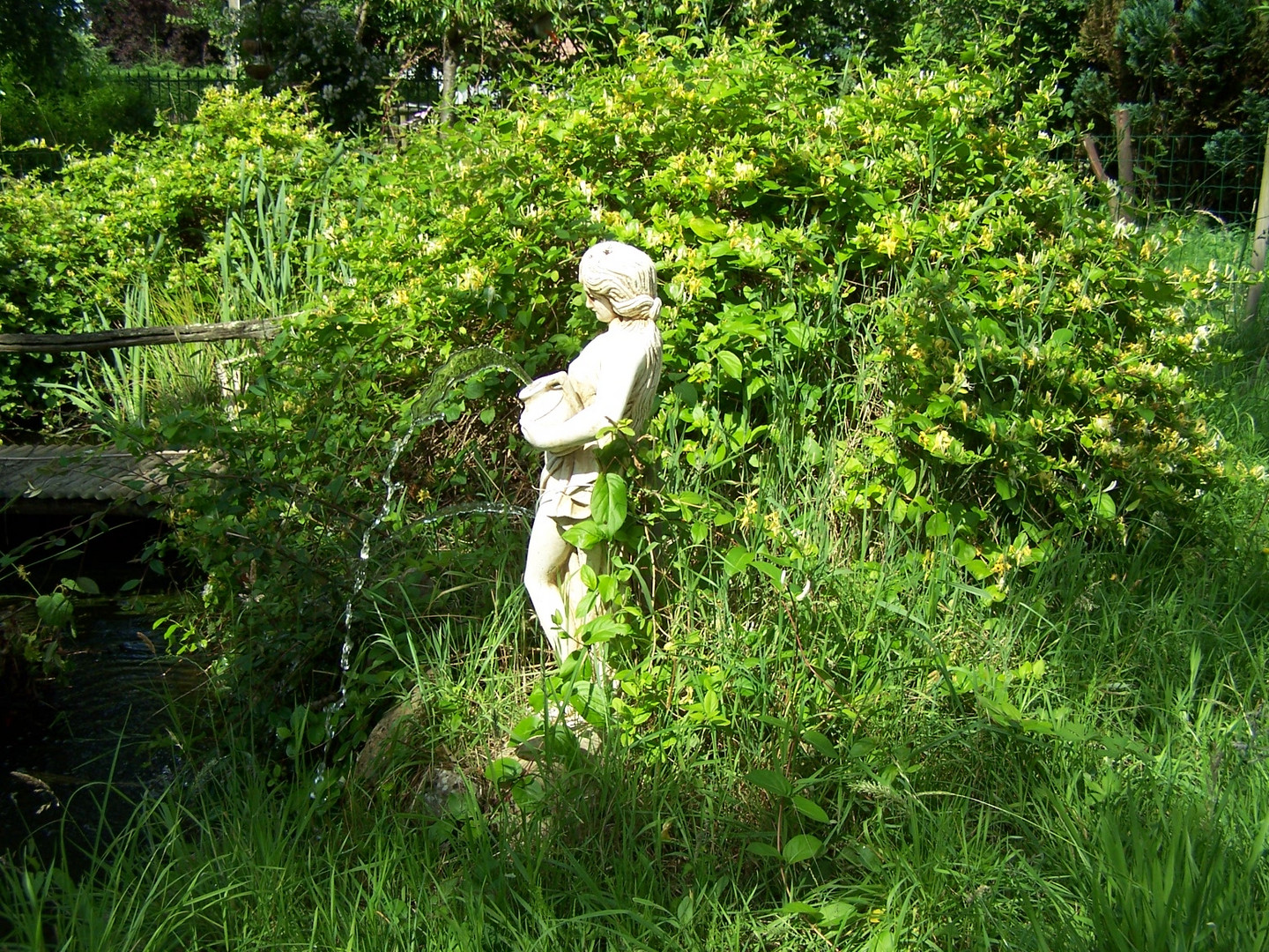 Statue de femme antique au bord du bassin dans le jardin