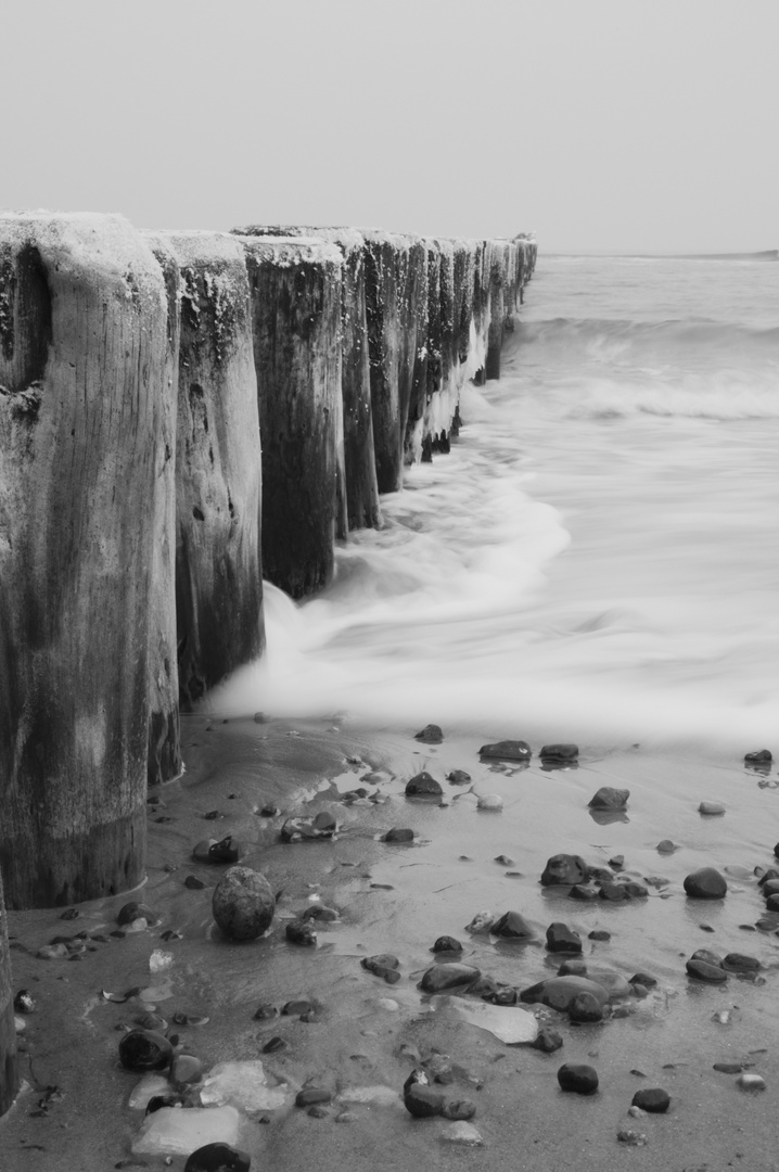 Steine an Holz mit Wasser im Sand