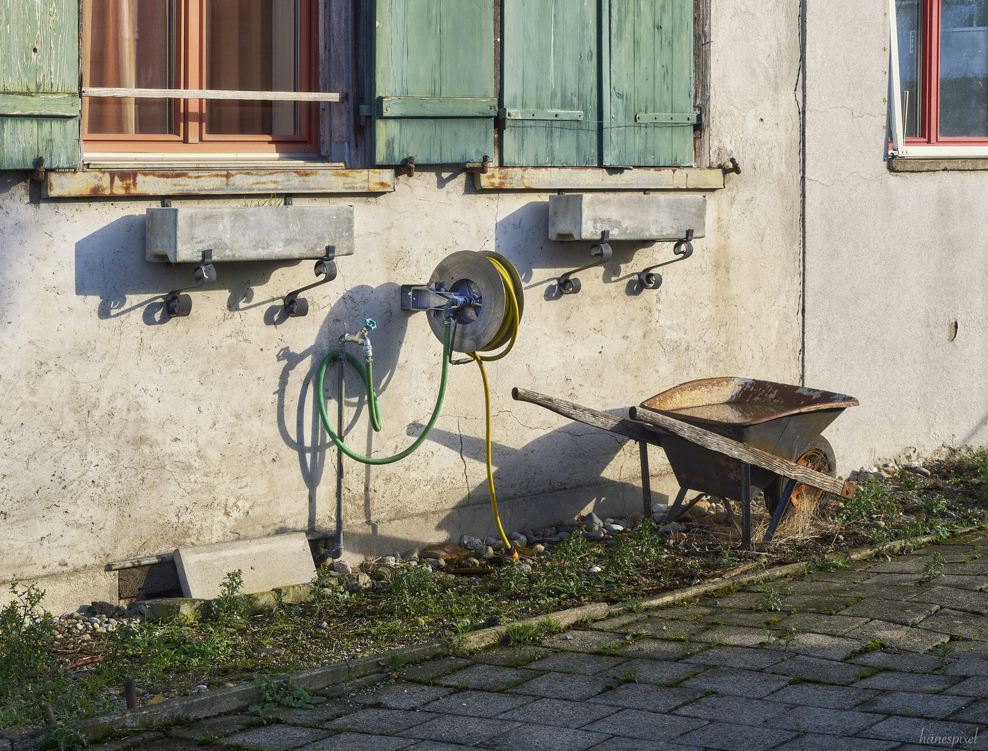 Stillleben mit Schubkarre und Gartenschlauch