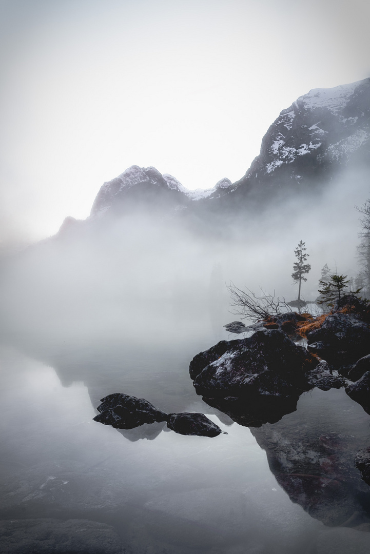 Stimmungsvoller See mit Bergen und Nebel