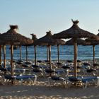 Strand mit Sonnenschirmen und Liegen in der Abenddämmerung