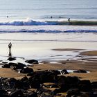 Strand mit Wellenreitern im Gegenlicht, Ireland