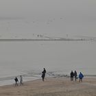 Strandspaziergänger am Borkumer Hauptstrand bei Hochwasser und Nebel