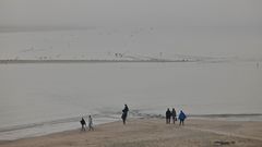 Strandspaziergänger am Borkumer Hauptstrand bei Hochwasser und Nebel