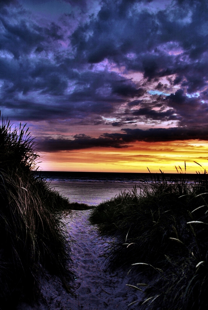 Strandsti zum Meer am Sonnenuntergang