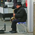 Straßenmusiker in der Fußgängerzone mit Saxophon auf Alditüte