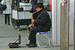 Straßenmusiker in der Fußgängerzone mit Saxophon auf Alditüte