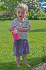 Tabea im Garten beim giessen.