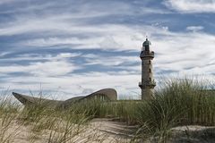 Teepott und Leuchtturm hinter Dünen