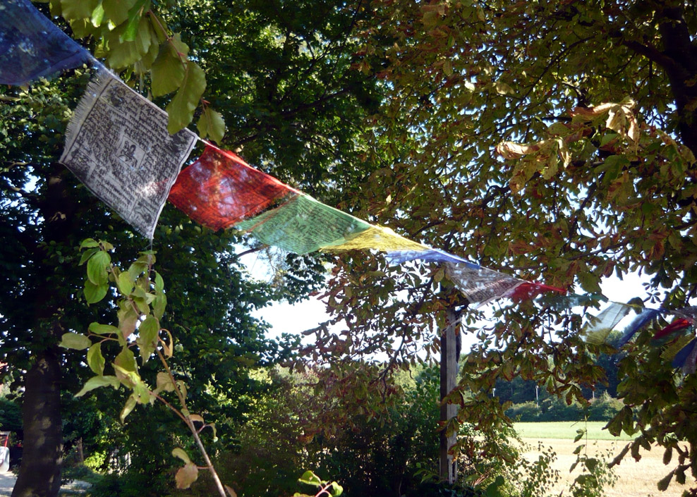 Tibetische Gebetstücher und Kreuz am Wegesrand