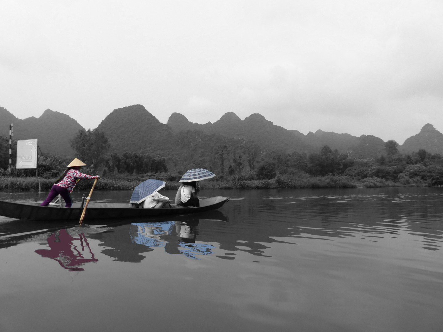 Touristen auf Langboot mit Sonnenschirm in Vietnam