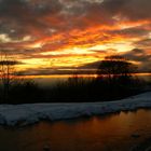 tramonto infuocato con neve e laghetto ghiacciato