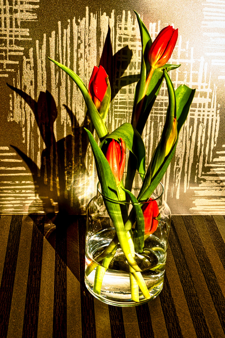 Tulpen in einer gläsernen Vase und Tapetenreste