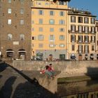 Turiste si riposano su un ponte sull'Arno