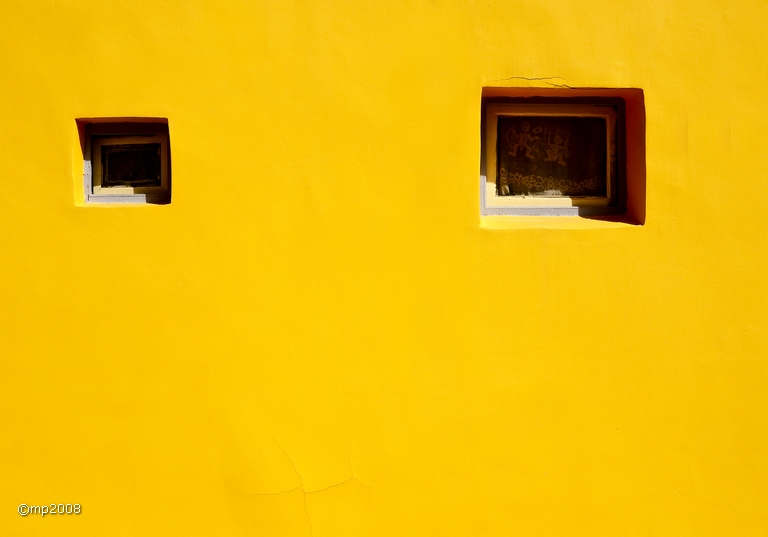 two windows on a yellow wall