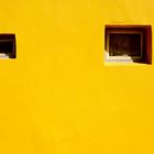 two windows on a yellow wall