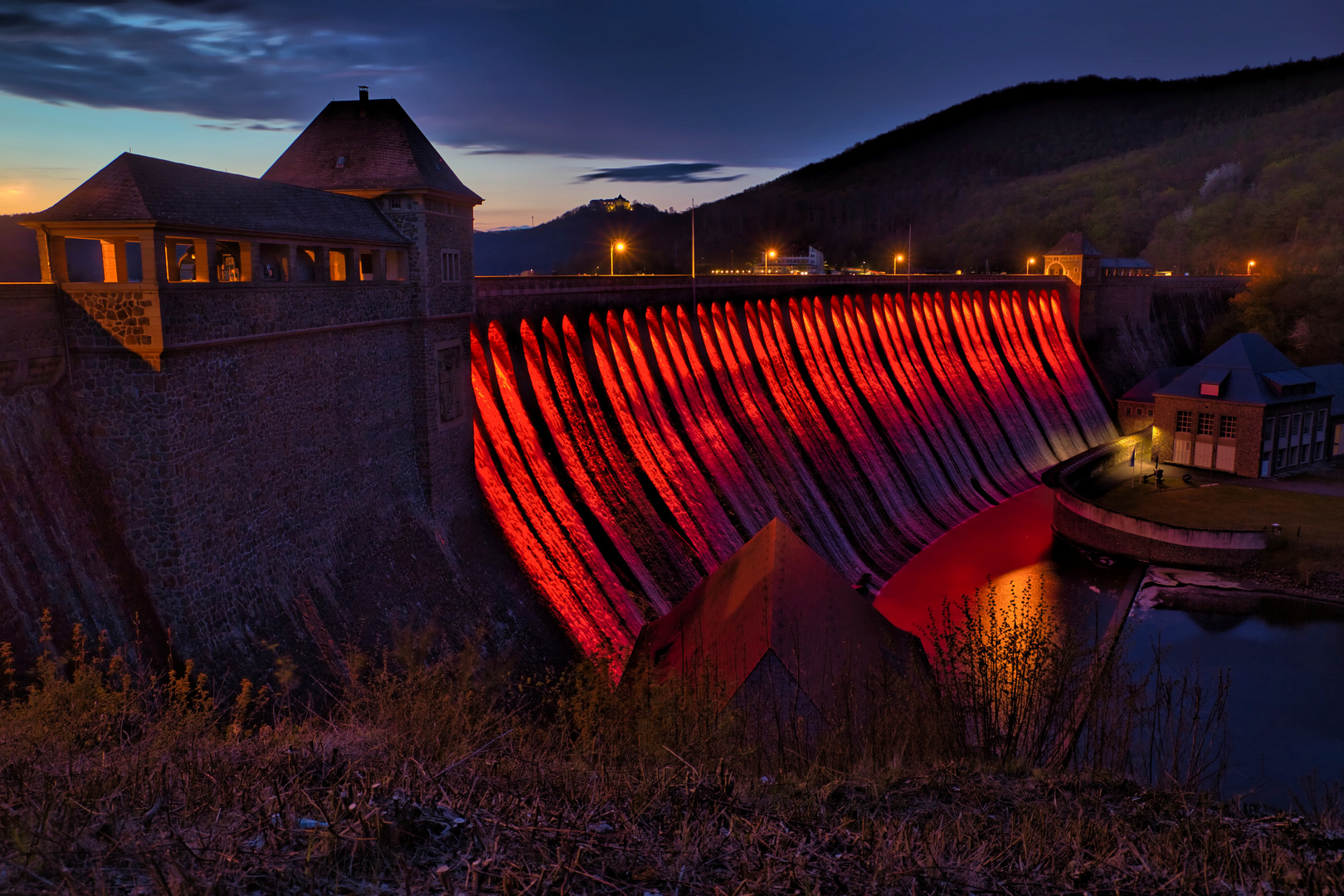 Überlaufende Edertalsperre in der roten Illumination.