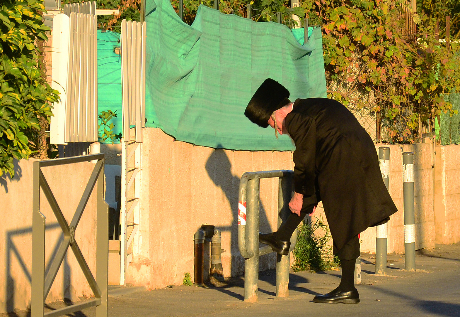 ultraorthodoxer Jude am Sabbatvorabend bei der Korrektur seiner Beinbekleidung auf offener Straße