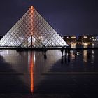 un éclair en néon rouge traverse la pyramide du Louvre