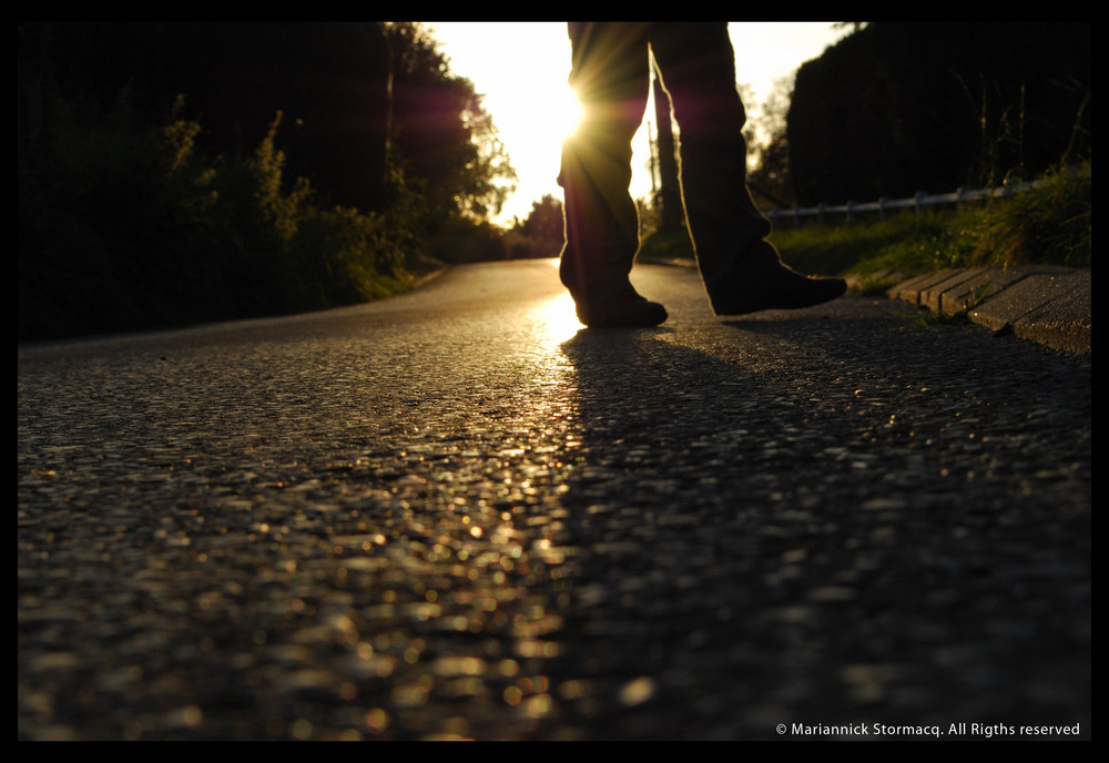 Un homme marche parmis les rayons du soleil.