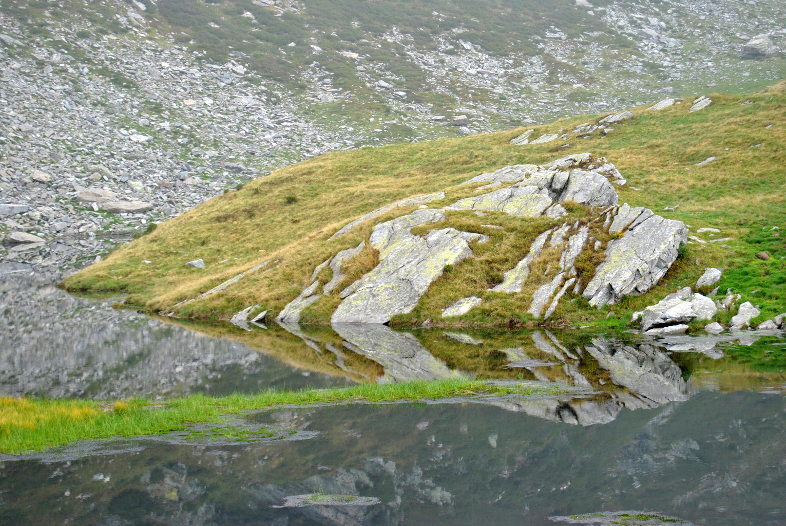 Una lingua d'erba nel lago avvolto dalle nubi