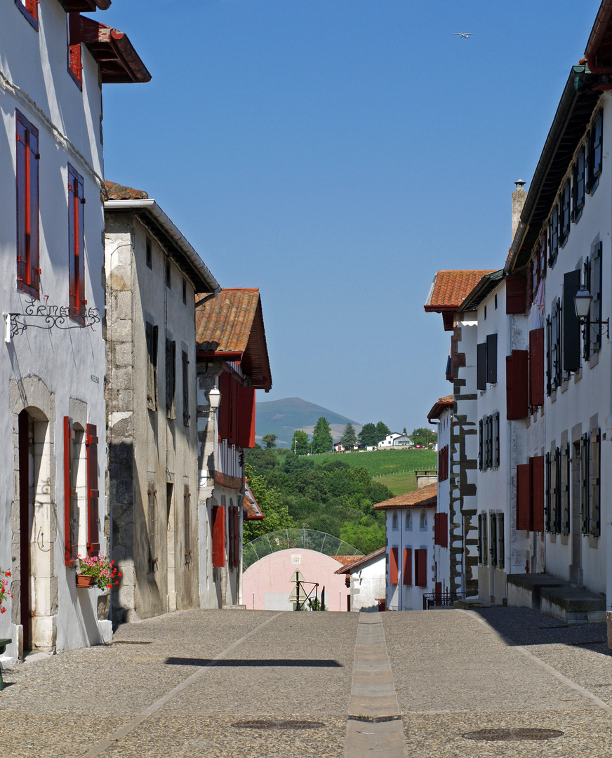 Une rue d’Espelette : vue sur les contreforts pyrénéens et l’incontournable fronton de pelote basque