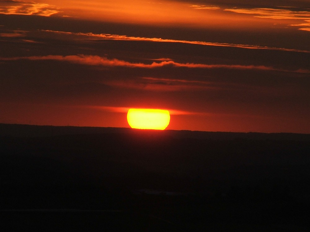 Untergehende Sonne, die den Horizont entlangkullert.