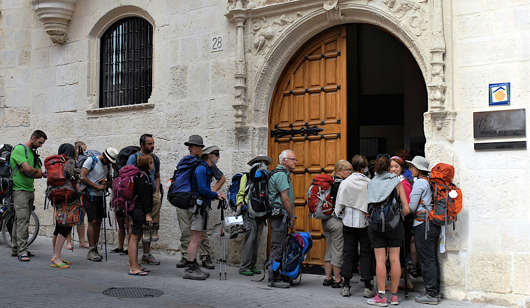 Unterwegs auf dem Camino de Santiago - Pilger warten auf Einlass in die Herberge in Burgos