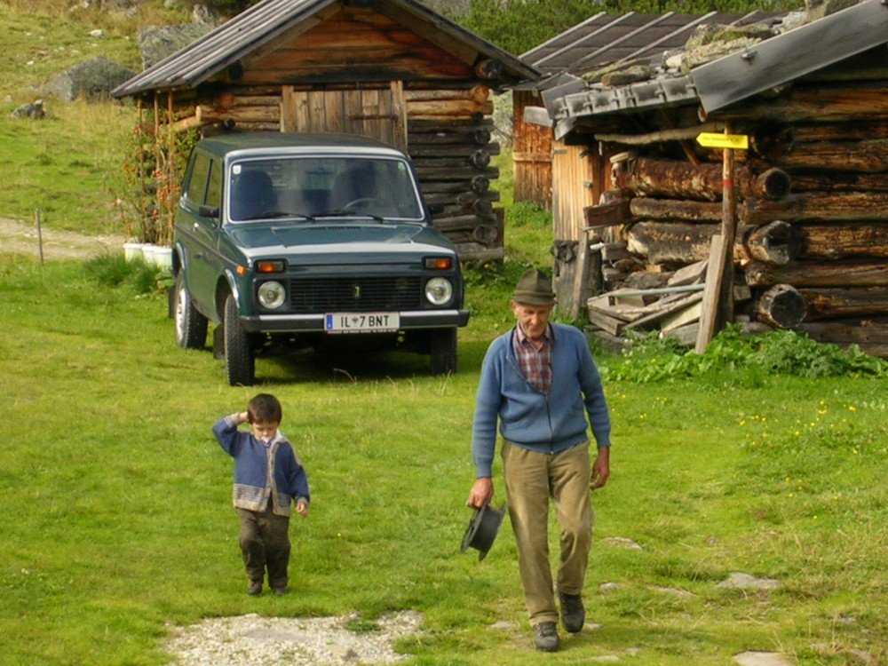 Urgrossvater und sein Enkel auf der Alm bei der Arbeit