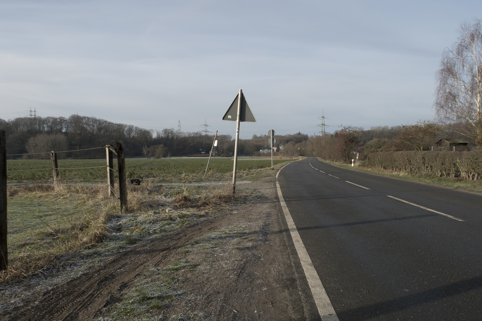 Verkehrsschilder an einsamer Straße in ländlichem Umfeld.