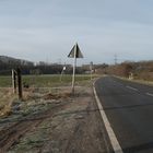 Verkehrsschilder an einsamer Straße in ländlichem Umfeld.