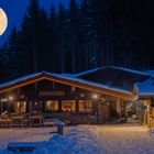 Vollmond über einer Hütte im Winter.