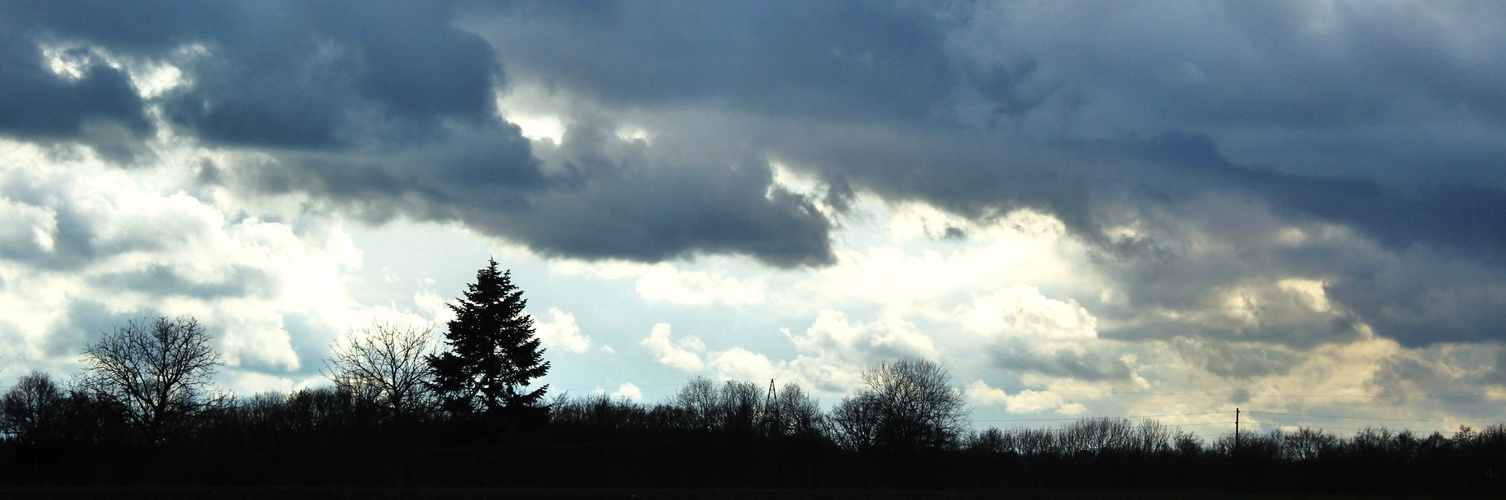 vorbei eilende Wolken über noch winterliche anmutenedem Land