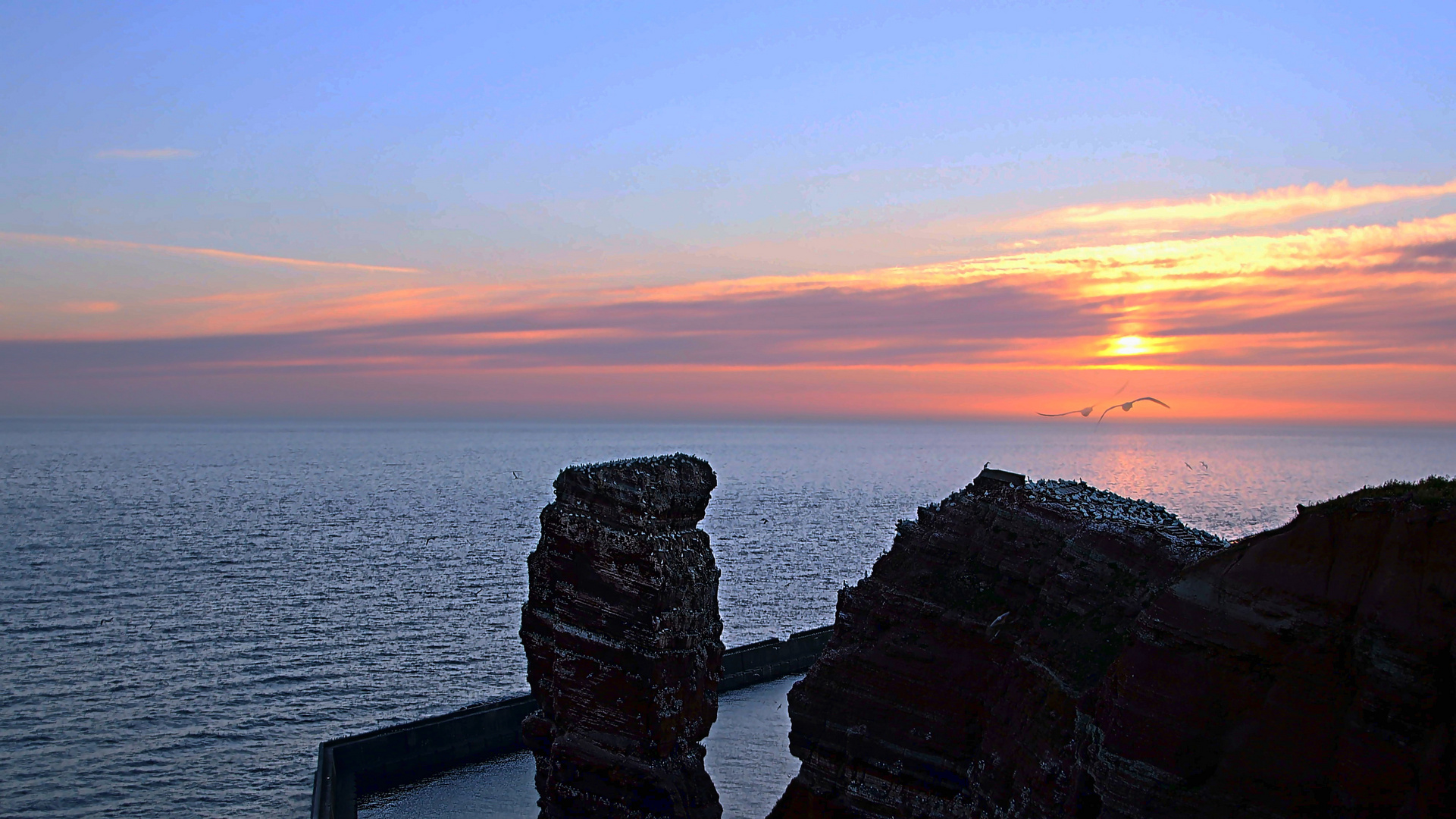 Wahrzeichen von Helgoland, Lange Anna (links im Bild) am Abend bei Sonnenuntergang